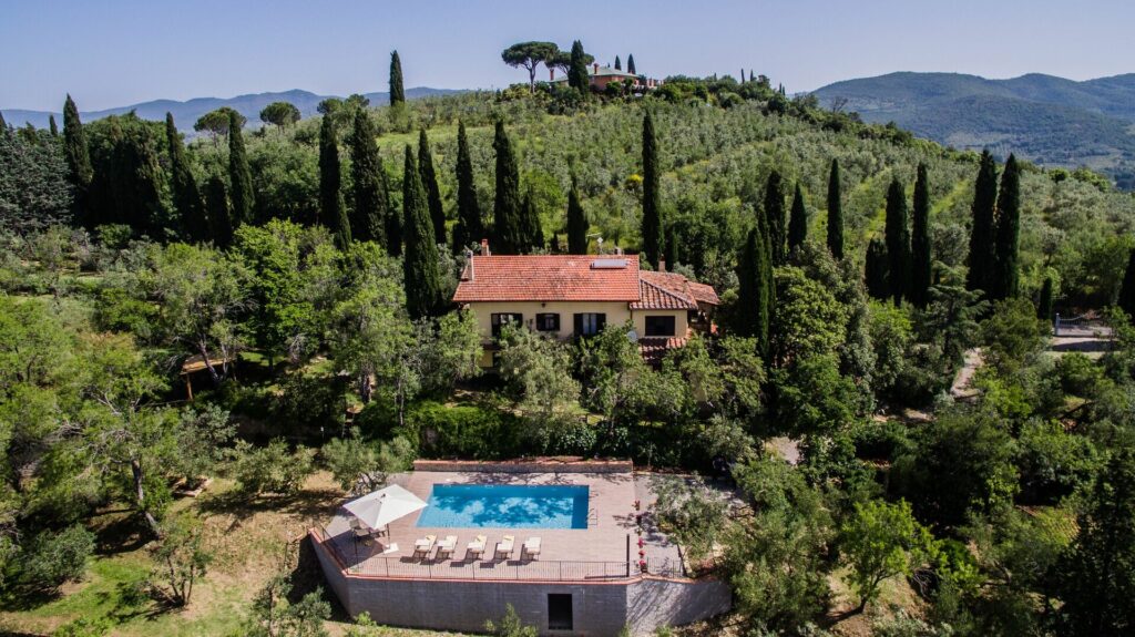 Villa de vacance en Toscane avec piscien, terasse, parasol et chaises longues vue sur vignes