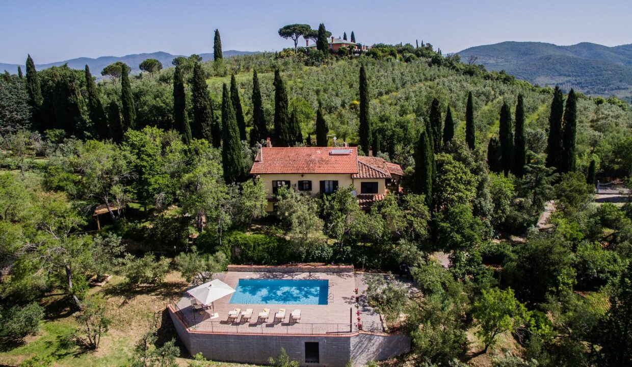 Villa de vacance en Toscane avec piscien, terasse, parasol et chaises longues vue sur vignes